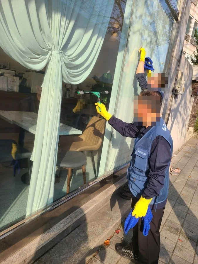 카페 외창청소 · 도구로 전면 유리를 닦는 작업자